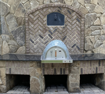 Custom outdoor kitchen featuring the HPC Fire Villa Series hybrid gas and wood built-in pizza oven