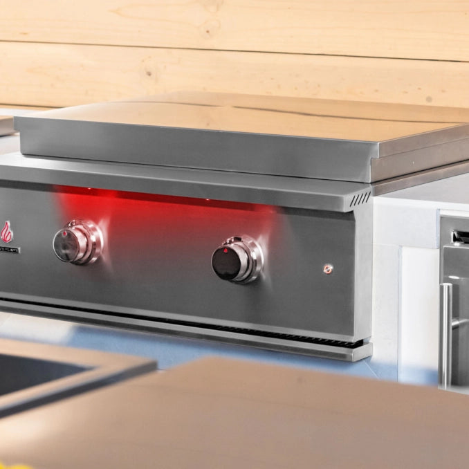 TrueFlame 30-Inch Built-In Gas Griddle with LED illuminated control knobs installed in a luxury outdoor kitchen